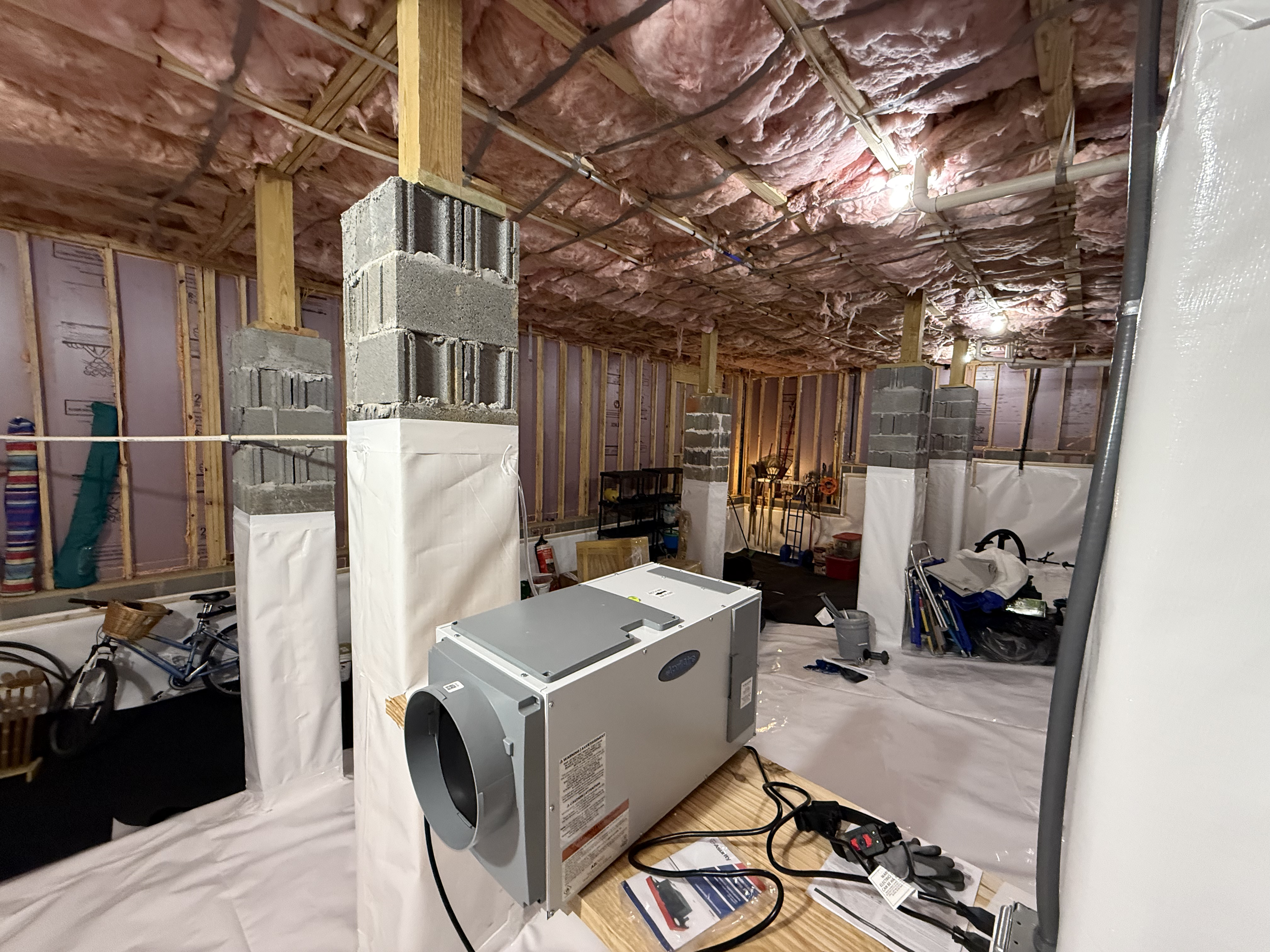 Wrapped support columns with white vapor barrier in newly encapsulated Chattanooga crawlspace