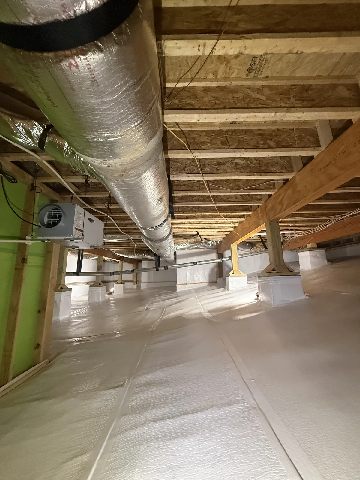 Spacious encapsulated crawlspace with white vapor barrier, wrapped columns, insulated ductwork and wall-mounted dehumidifier, Chattanooga Tennessee